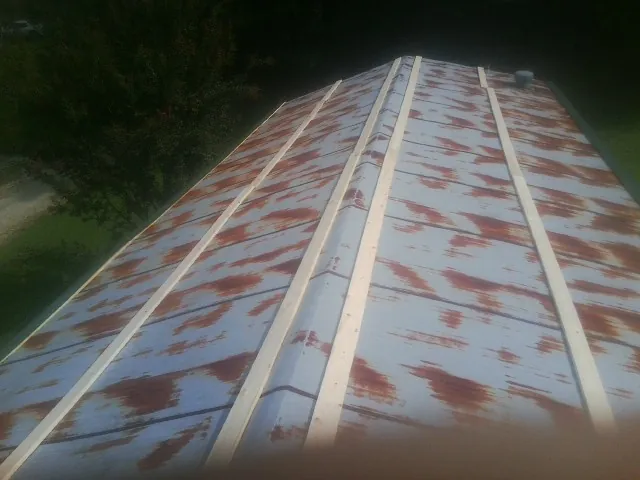 Rusted metal roof panels with new wood purlins before replacement — Storm Damage Roof Repair in South Fulton by Roofing Brothers