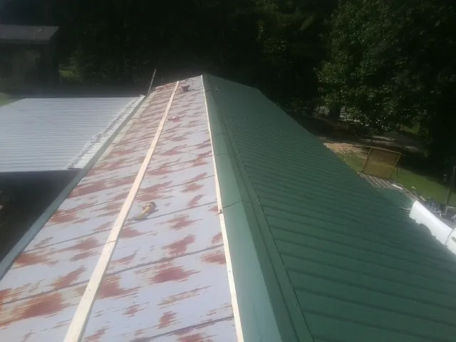 Old rusted panels beside newly installed green metal roofing — Wind Damage Roof Repair by Roofing Brothers in South Fulton