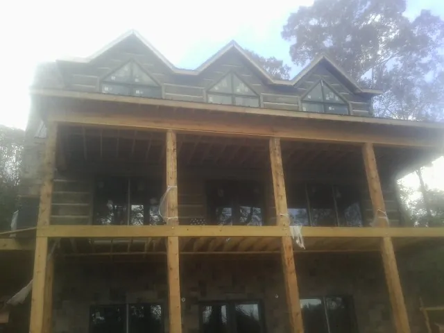 Dormers and porch framing on a large log home under construction — Roof Coating work by our crew in South Fulton