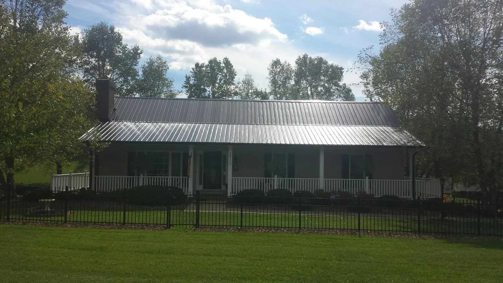 Gray metal roof on a brick ranch with a full width front porch — Gutter Guard Installation work by our crew in South Fulton