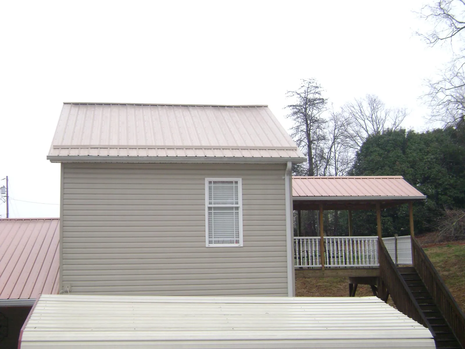 Tan metal roofs on a two story addition and attached porch, from a Roof Replacement job in South Fulton