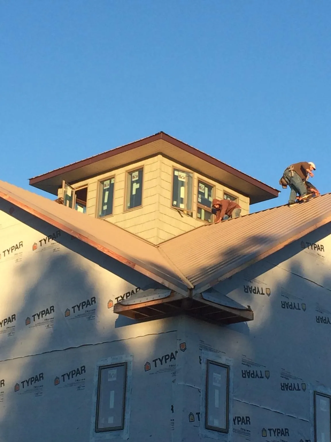 Roofers working around a rooftop cupola on a new metal roof at sunset — Roof Waterproofing in South Fulton by Roofing Brothers